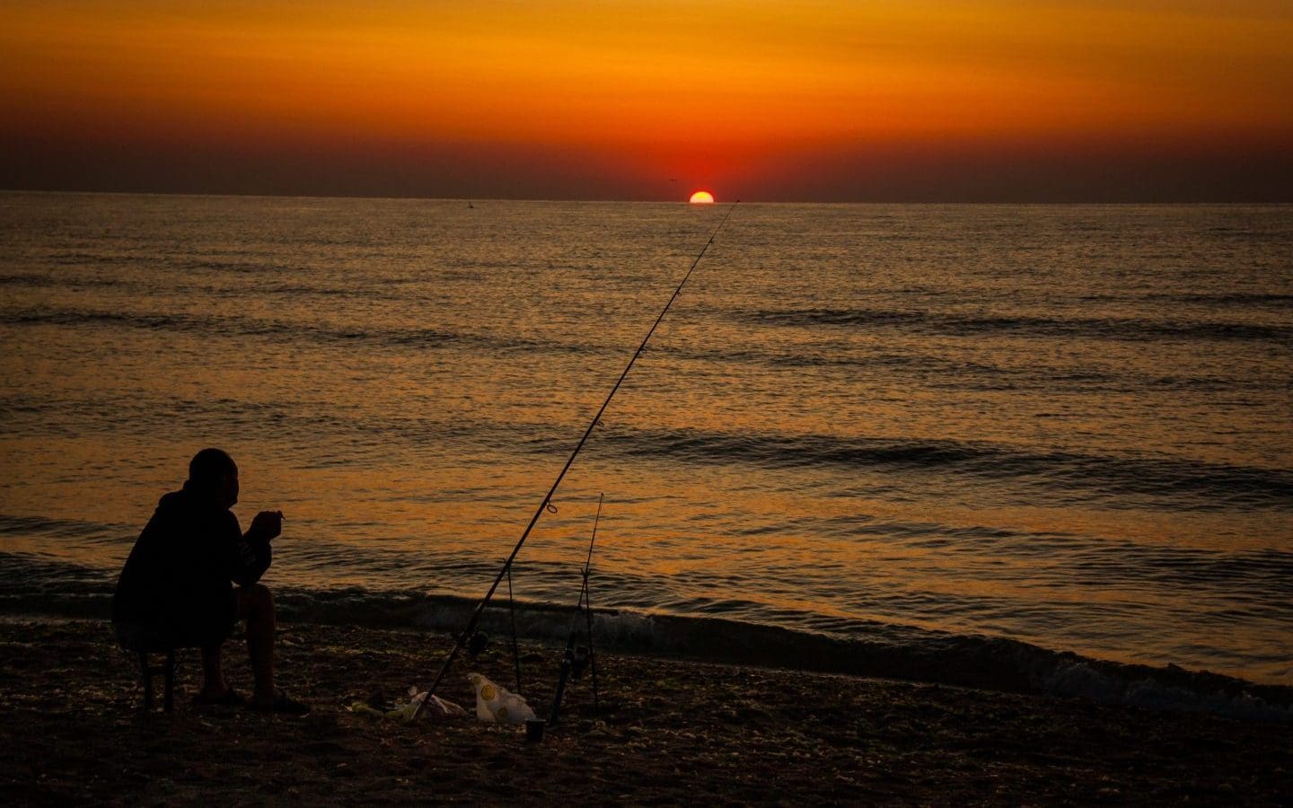 silhouette-man-fishing-sea-against-orange-sky